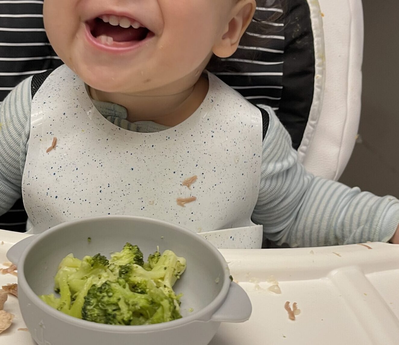 Happy toddler eating broccoli