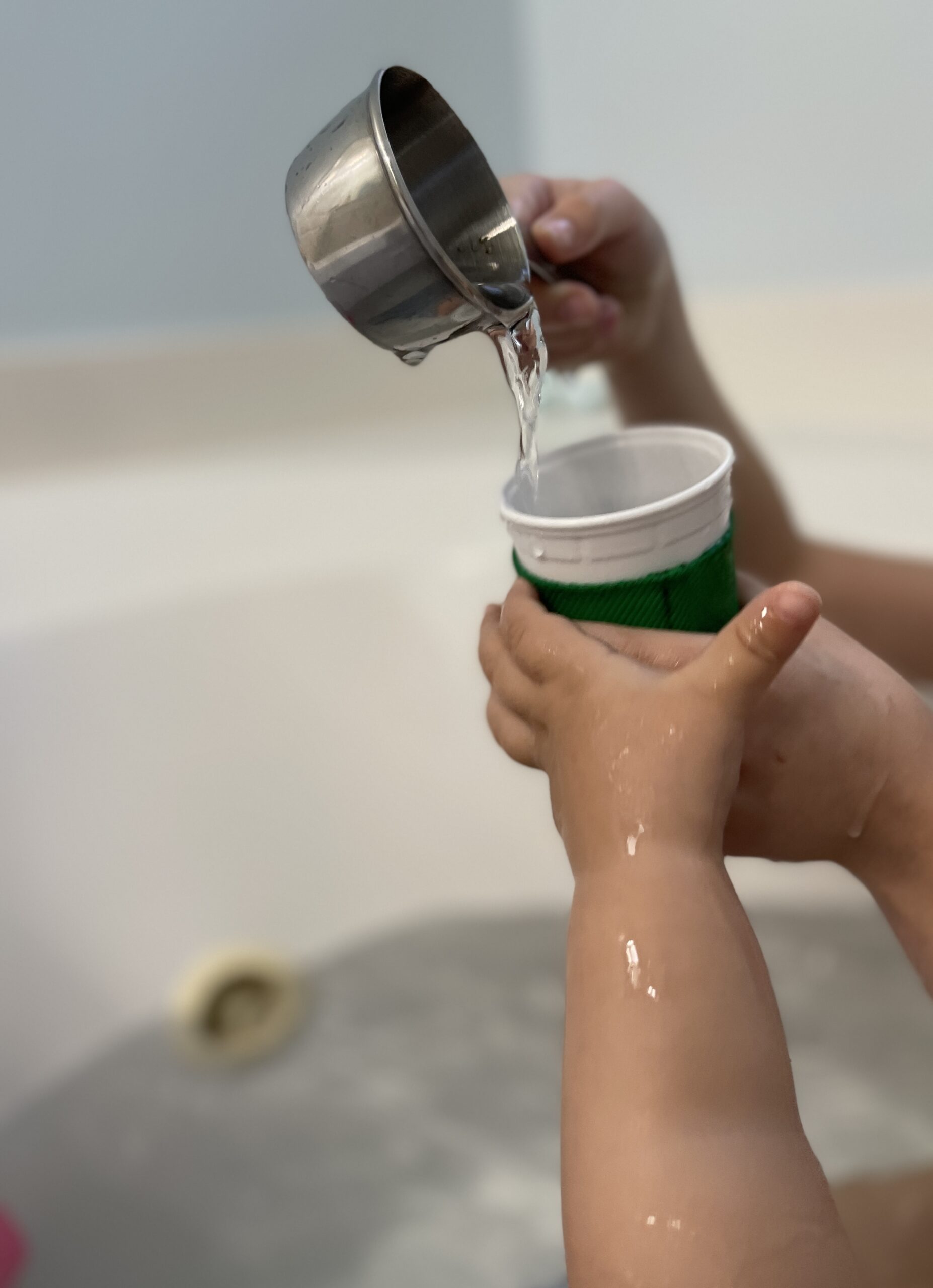 kids hands pouring bath water into play coffee cup