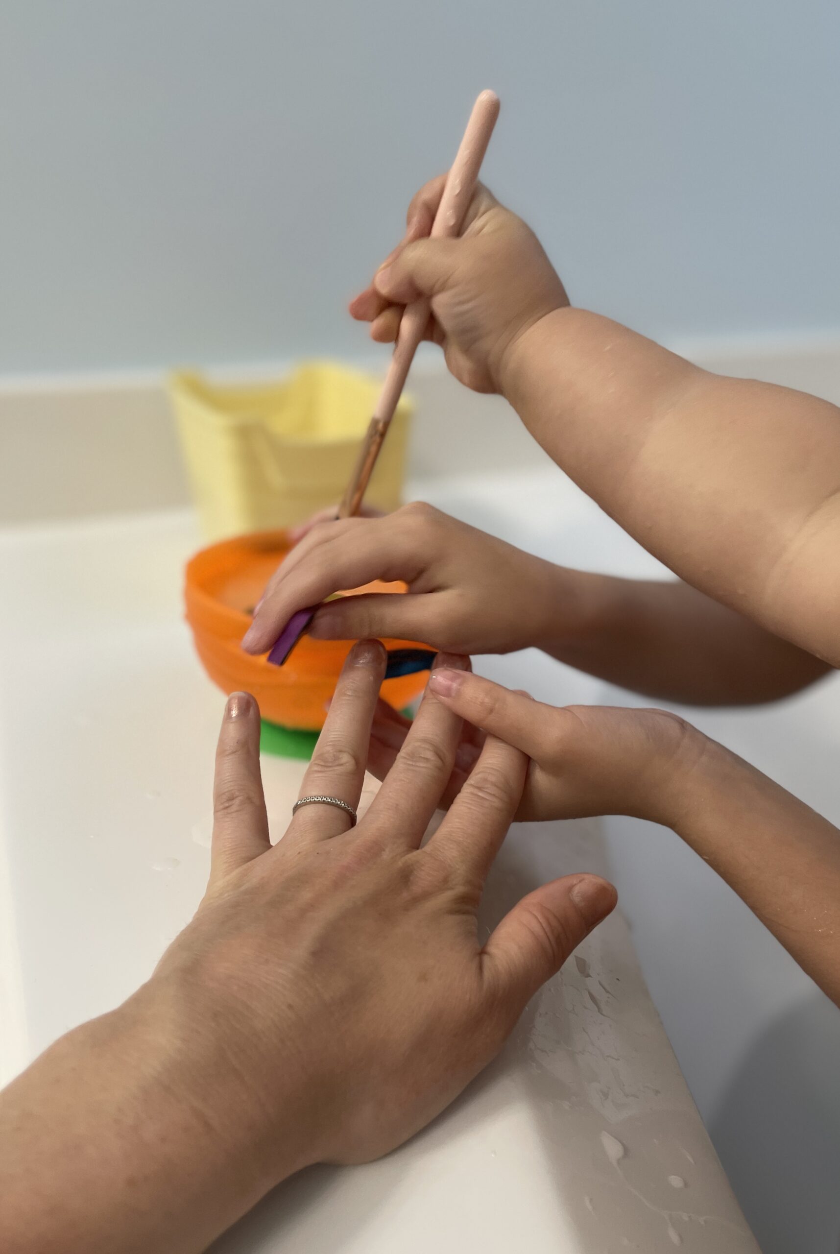 kid hands holding makeup brushes in bath tub