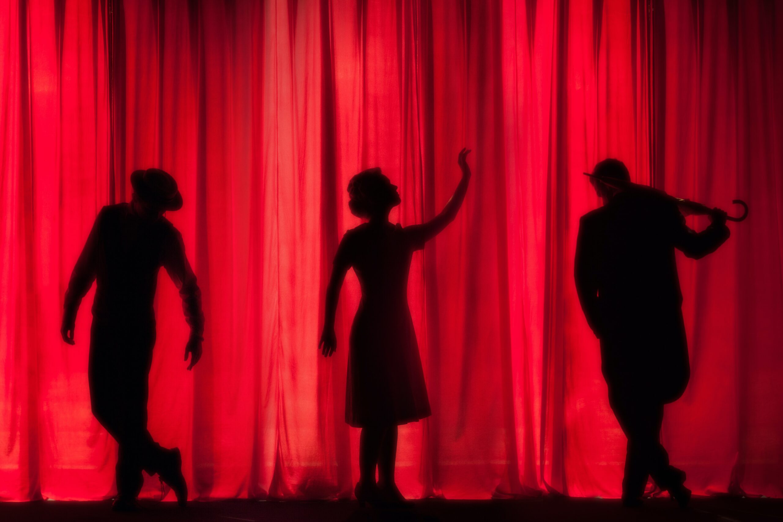 silhouettes on stage with red curtain